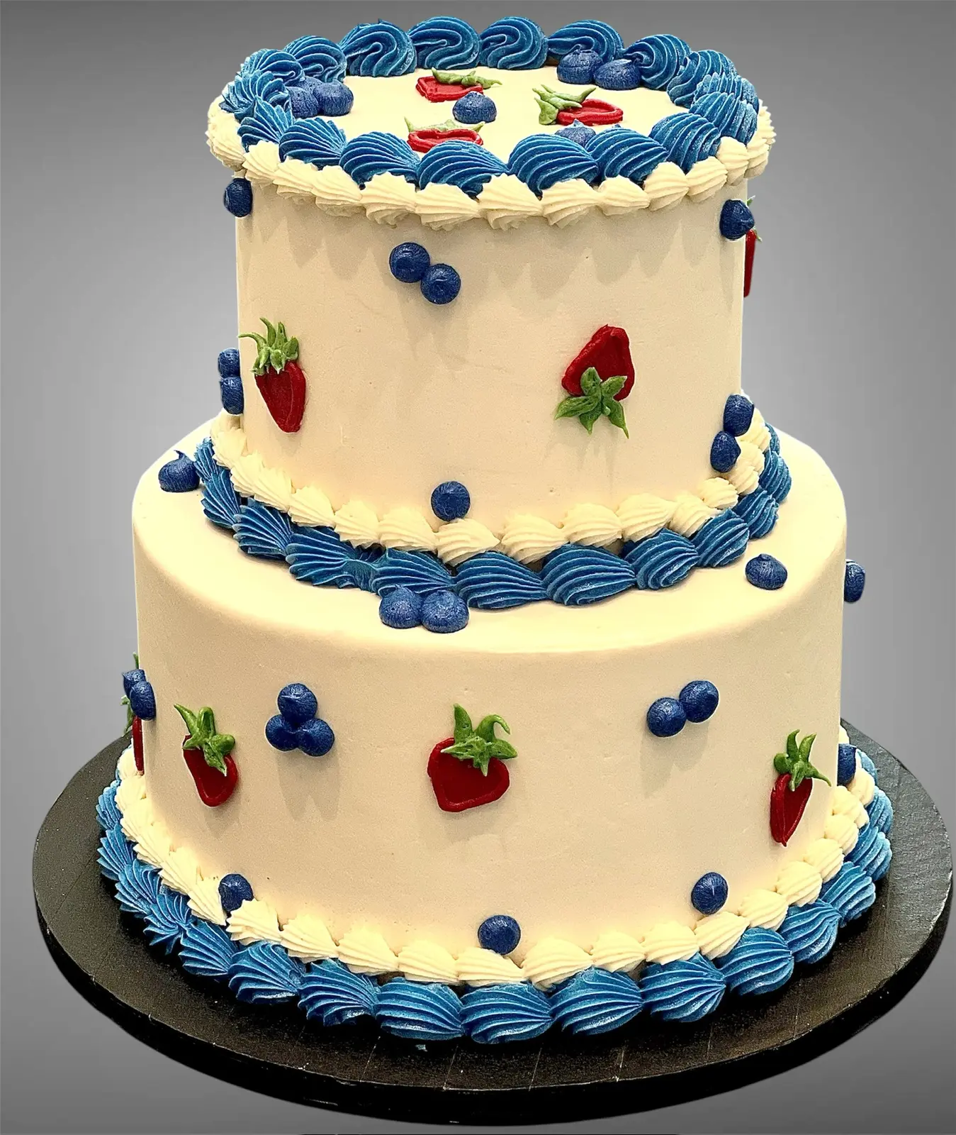 Two-tier custom cake with blue trim and strawberries