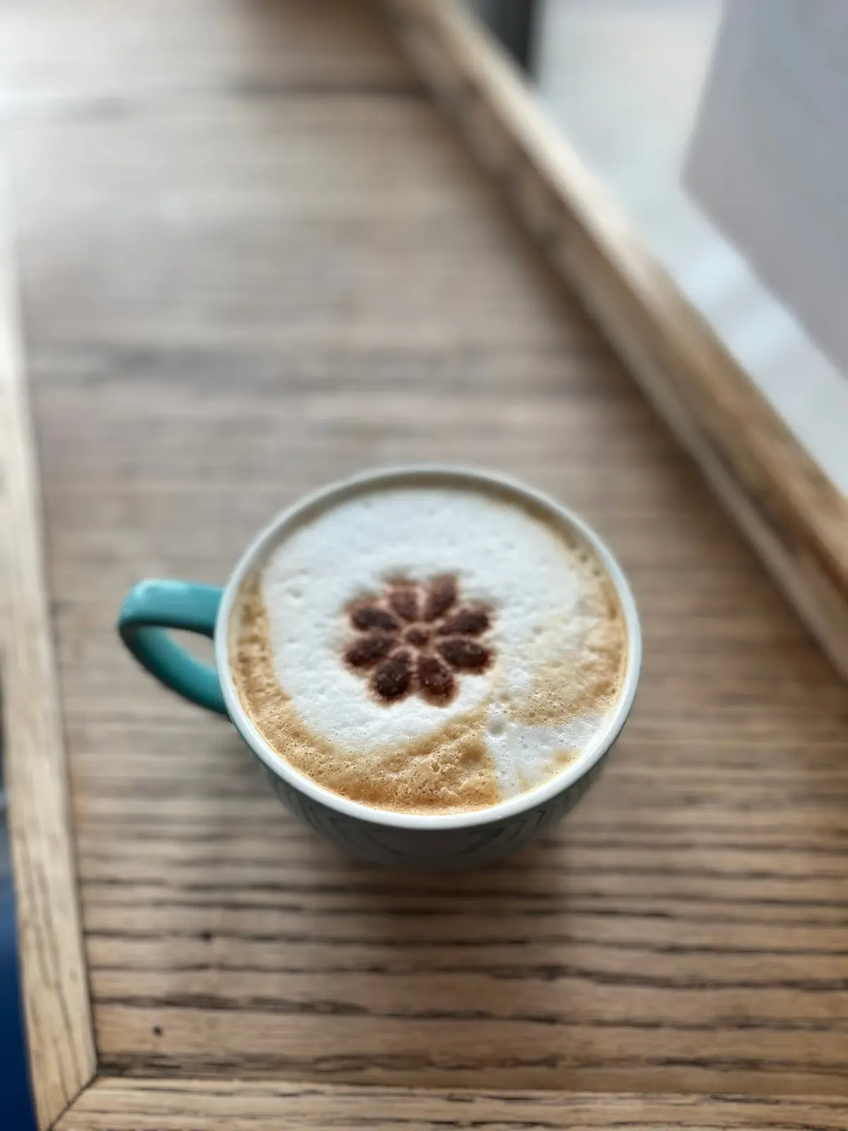 A flower-topped latte on a wooden counter